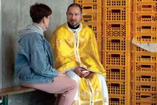 Lt. Glib Pistruga, a Chaplain from Canadian Forces Base Kingston, Ont., provides spiritual support to a Ukrainian woman at a reception centre in support of Operation REASSURANCE in Warsaw, Poland, on April 23.