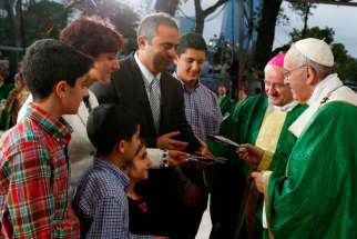 Pope Francis gives a copy of the Gospel of Luke to a family during the closing Mass of the World Meeting of Families on Benjamin Franklin Parkway in Philadelphia Sept. 27.
