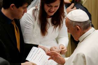 Pope Francis blesses the marriage certificate of a U.S. couple during his general audience in Paul VI hall at the Vatican Dec. 14, 2016.