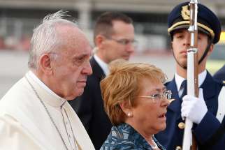 Pope Francis walks with Chilean President Michelle Bachelet as he arrives at the international airport in Santiago, Chile, Jan. 15.