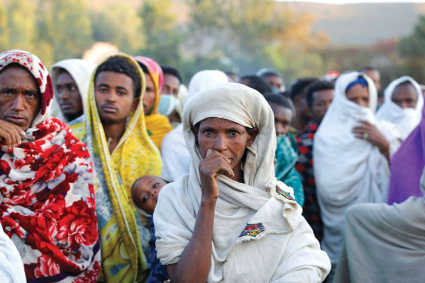 People displaced by fighting in Ethiopia’s Tigray region wait in line to receive food donations at a temporary shelter in the town of Shire.
