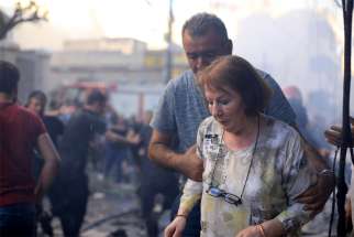 A woman is assisted at the site of a car bomb blast outside the Syriac Orthodox Church of the Blessed Virgin Mary in Qamishli, Syria, July 11, 2019. At least 11 people were injured in the blast during evening services. It was unclear who was responsible for the attack.