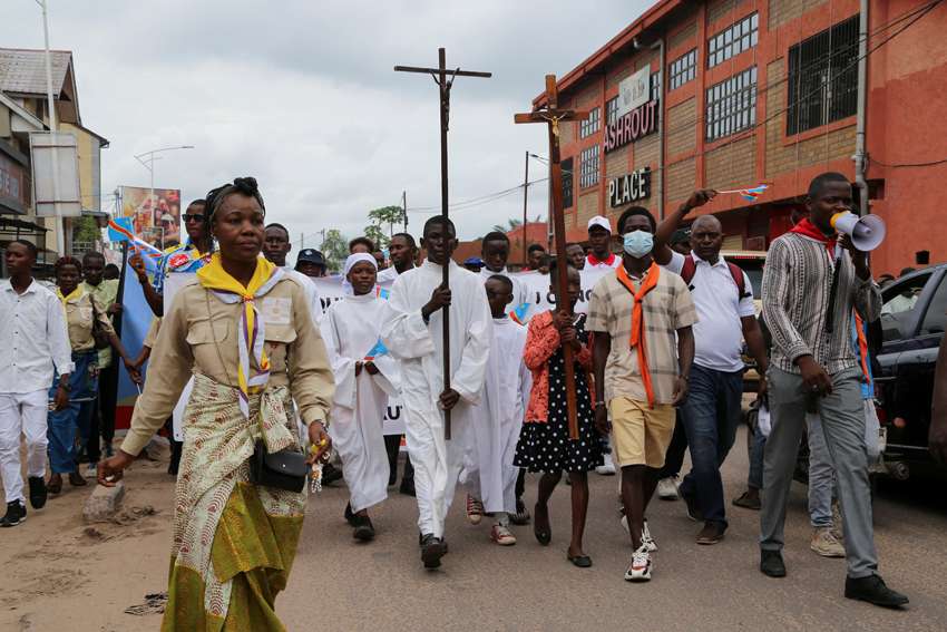 A young woman in Kinshasa, Congo, carries a cross during a march to protest escalating violence in the the country, Dec. 4, 2022.