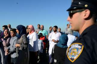 A member of the New York City Police Department stands guard during a group prayer session for the Muslim holiday Eid al-Adha in the Brooklyn borough of New York City on Aug. 12, 2016.