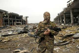 A member of the self-proclaimed Donetsk People&#039;s Republic forces stands guard near buildings destroyed during battles with Ukrainian armed forces, at Donetsk airport, Ukraine, June 1. Pope Francis has established a committee to distribute aid in Ukraine with an ecumenical, interreligious approach.