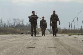 Service members of the Ukrainian armed forces walk along a road near the line of separation outside the rebel-controlled city of Donetsk April 26, 2021.